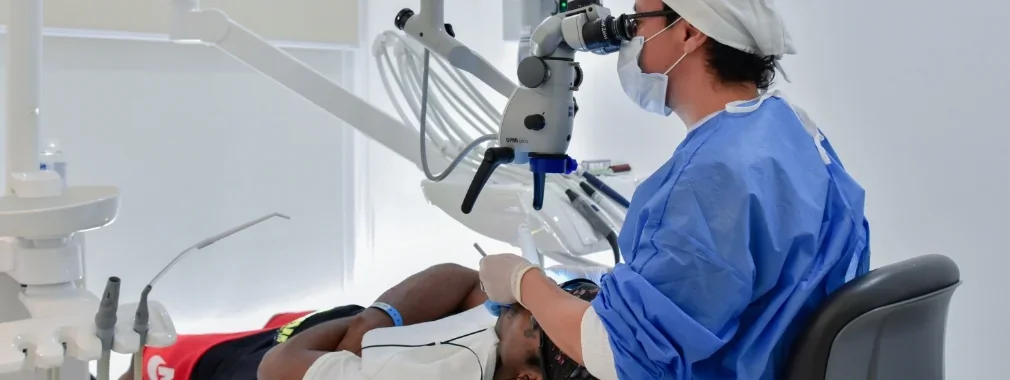 Specialist using a high-tech surgical microscope to ensure clinical precision during a dental implant procedure.